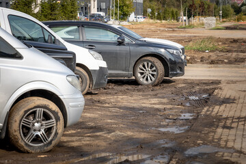 Several different dusty and dirty cars are parked in the mud. Lack of parking in the residential area of the city. Car wheels in mud. Parking in the wrong place - Powered by Adobe