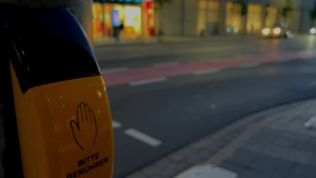 A button for pedestrians at a traffic light in Germany, a yellow body and a flashing red inscription in German  says "Signal kommt" (signal comes) and "Bitte ber&uuml;hren" (please touch) down below.