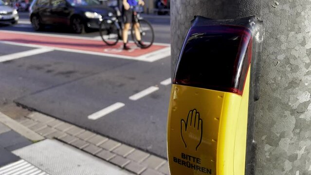 A button for pedestrians at a traffic light in Germany, a yellow body and a flashing red inscription in German  says "Signal kommt" (signal comes) and "Bitte ber&uuml;hren" (please touch) down below.
