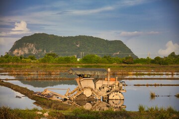 an old dump truck sitting in a flooded field with mountains