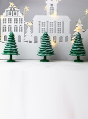 Three snow-covered spruce trees against the background of a fairy-tale town. Christmas Decorations