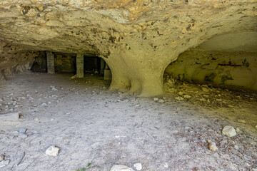 Cave with tunnels and concrete supports or columns in background, walls with uniform texture and...