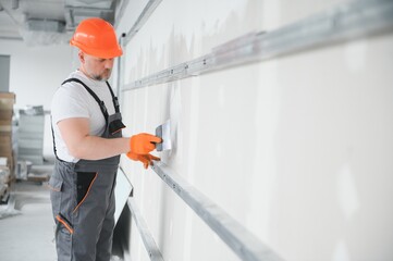 apartment interior construction - worker plastering gypsum board wall
