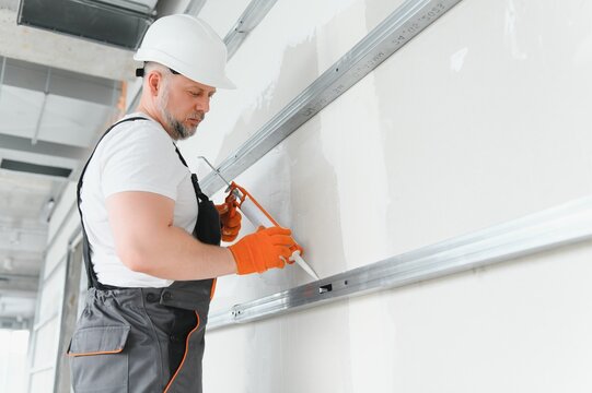 The builder fills the seam between plasterboard plates a silicone gun