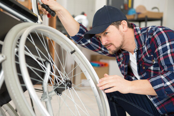 man is repairing a wheelchair at workshop