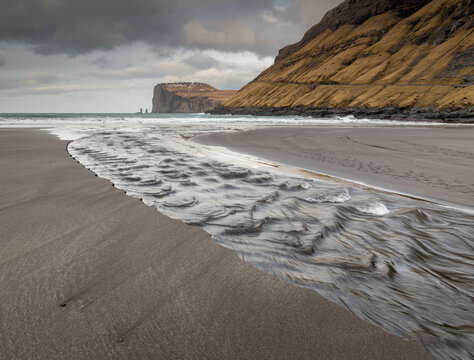 Channel running into the ocean looking towards the cliffs and sea stacks of Risin and Kellingin, Tjornuvik, Faroe Islands, Denmark