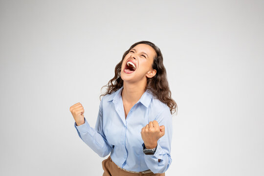 Angry, unhappy, despaired, depressed young european woman in formal wear screams, freaking out with fists