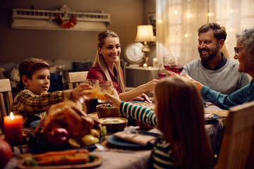 Happy extended family toasts during Thanksgiving dinner at dining table.