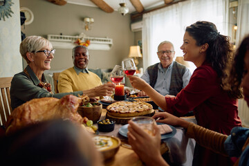 Fototapeta na wymiar Happy women toasting while celebrating Thanksgiving with their family at dining table.