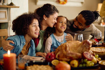 Happy multiracial family enjoys on Thanksgiving at dining table.
