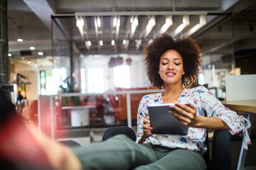 Relaxed young woman using a digital tablet at the office