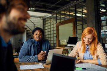 Obraz premium Young and diverse group of designers having a meeting in an office while working in a startup company