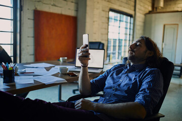 Relaxed young man using a smartphone in a office