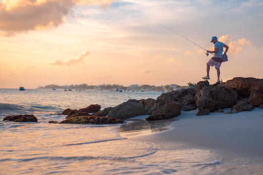 A local fisherman at sunset with calm water and orange sky on the south coast of Barbados, West Indies, Caribbean