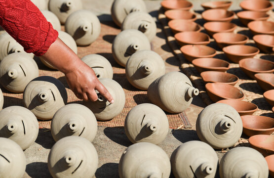 A craftswoman shows off the traditional clay pots she left to dry in the sun, Bhaktapur, Nepal