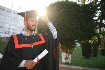 Portrait of indian handsome male graduate in graduation robe.