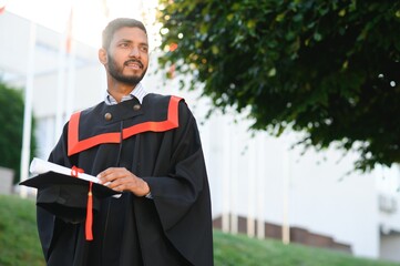 Portrait of indian handsome male graduate in graduation robe.