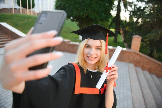 Female graduating student in bachelor robe taking selfie on her graduation day
