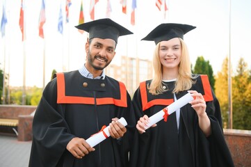 education, graduation and people concept - happy international students in mortar boards and bachelor gowns.