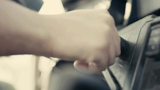 Closeup of man putting car key to the keyhole, starting the car or stopping engine sitting on driver's seat.