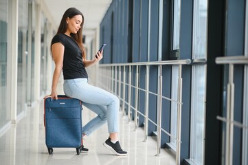 tourism, holiday, vacation, childhood and transportation concept - smiling little girl with travel bag over airport background