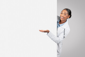 Positive millennial african american lady doctor with big banner point hand at copy space - obrazy, fototapety, plakaty