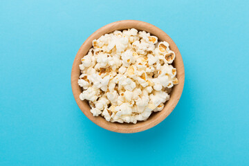Tasty popcorn in bowl on color background, top view