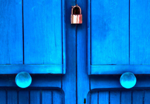 Blue doors with round knobs and a padlock to lock them closed together; Venice, Italy
