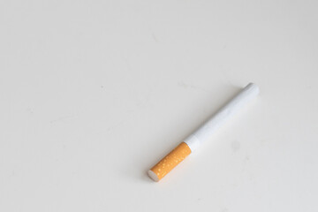 A cigarette is placed on a white table. Take a photo in the studio