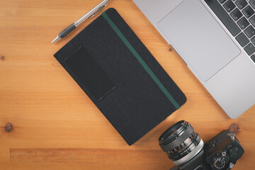 Top view of grunge cement table with computer laptop, camera, notebook and pen in concept of...