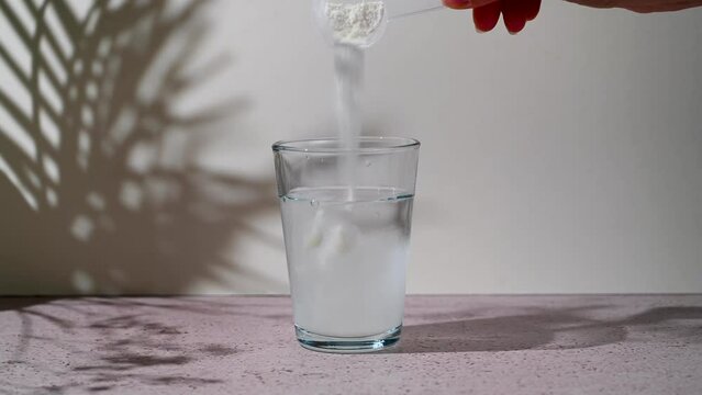 Collagen protein powder pouring in a glass with water. Food beauty and health supplement