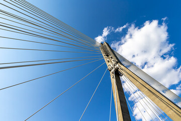Obraz premium Fixing the ropes in the concrete pylon of the rope bridge. View of the bridge structures against the blue sky