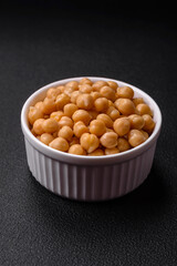 Delicious canned chickpeas in a ceramic plate on a dark concrete background
