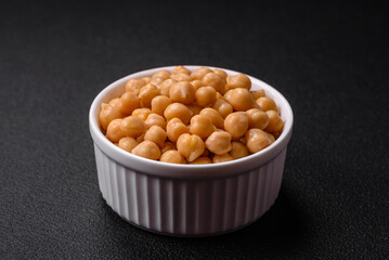 Delicious canned chickpeas in a ceramic plate on a dark concrete background