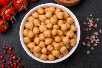 Delicious canned chickpeas in a ceramic plate on a dark concrete background