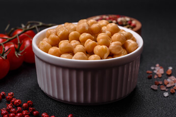 Delicious canned chickpeas in a ceramic plate on a dark concrete background