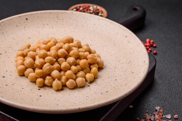 Delicious canned chickpeas in a ceramic plate on a dark concrete background