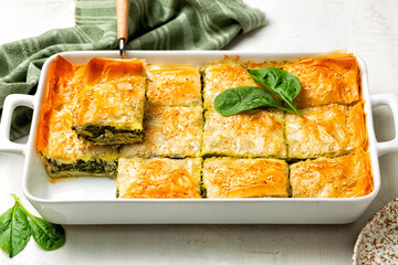 Casserol Spanakopita piece of pie, homemade Greek spinach pastry. With cheese feta, chopped spinach, green, egg, layered in phyllo or filo dought. 