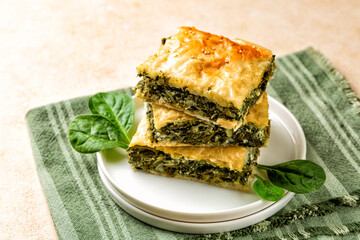 Stack of Spanakopita piece of pie, homemade Greek savory spinach pastry. It contains cheese feta,...