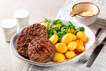Homemade dinner. Meat patties with baked potatoes and salad, mayonnaise. Beef Cutlets, burgers or hamburger.
