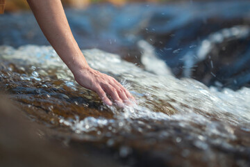 Close up hand of traveler woman touching water in the forest from waterfall, Tourist travel...