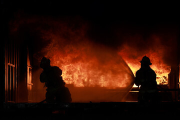 Two Firefighters practice to close the frame of fire and smoke from inside of the closed room