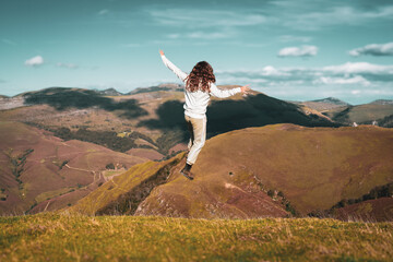 une jeune enfant saute en l'air devant un paysage de montagnes en automne - 666754743