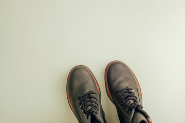 Trendy dark green boots pair on light green background. Shoe sale, fashion concept. Stylish shoes for hiking. Top view, flat lay, copy space