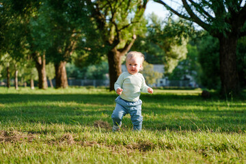 Happy little child baby 1 year in the park in summer, outdoor walking