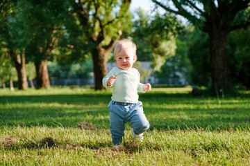 Happy little child baby 1 year in the park in summer, outdoor walking