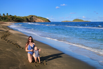 Young woman with a baby standing at Bathway Beach on Grenada Island, Grenada.