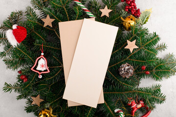 Fototapeta na wymiar Christmas vertical menu card mockup and Christmas decoration on a natural fresh green fir branch. Christmas invitation card mockup 4x9 ratio. Flat lay, top view