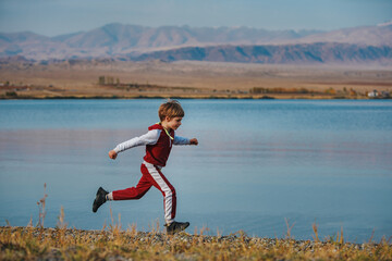Active boy running on the lake shore