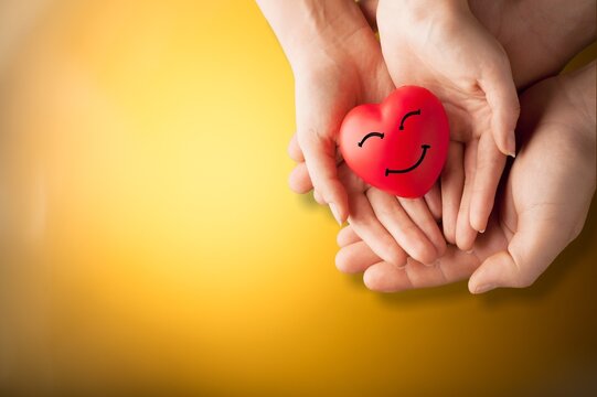 Hands holding a heart with happy face